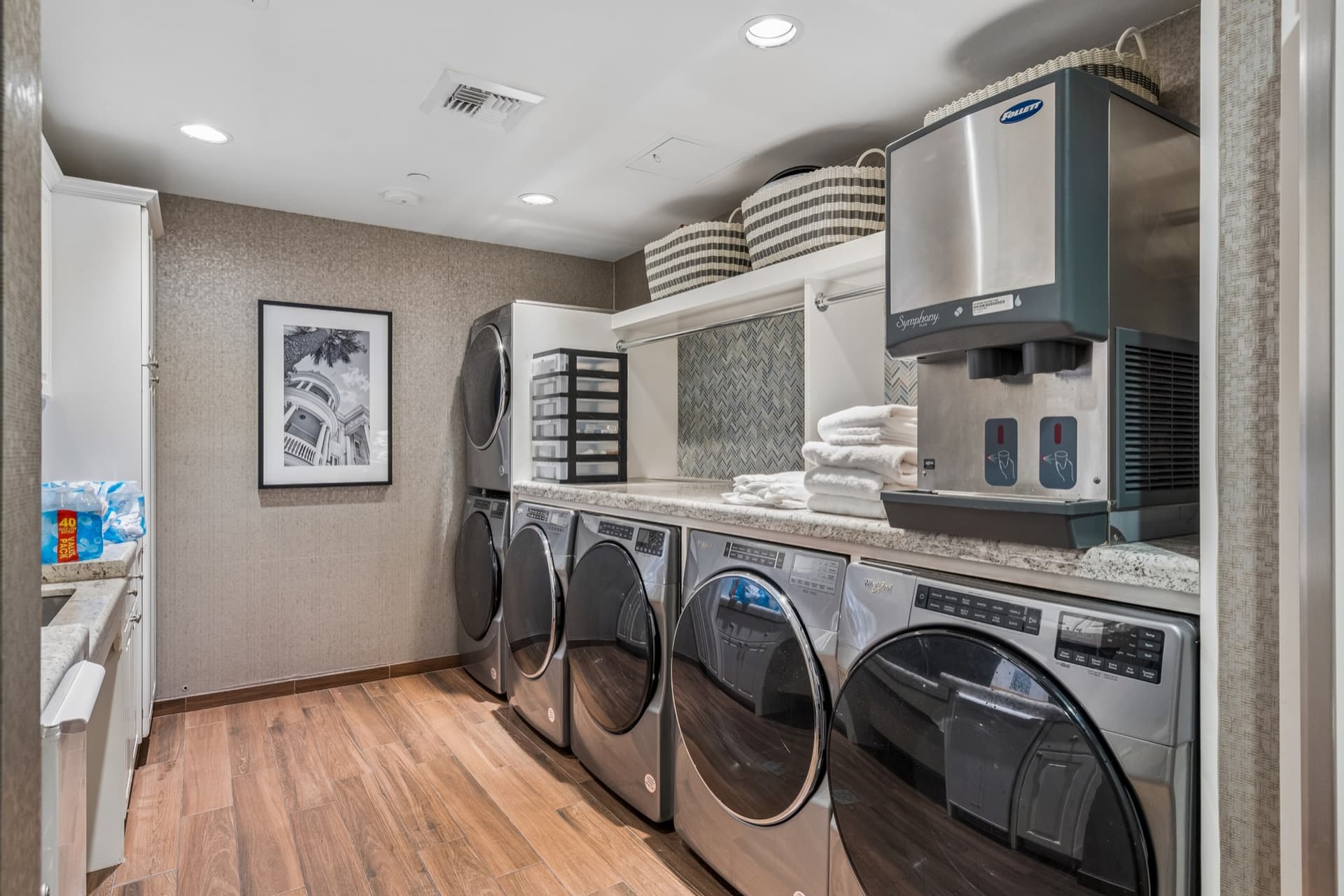 Community laundry room with multiple commercial washers and dryers, folded towels, and an ice machine.