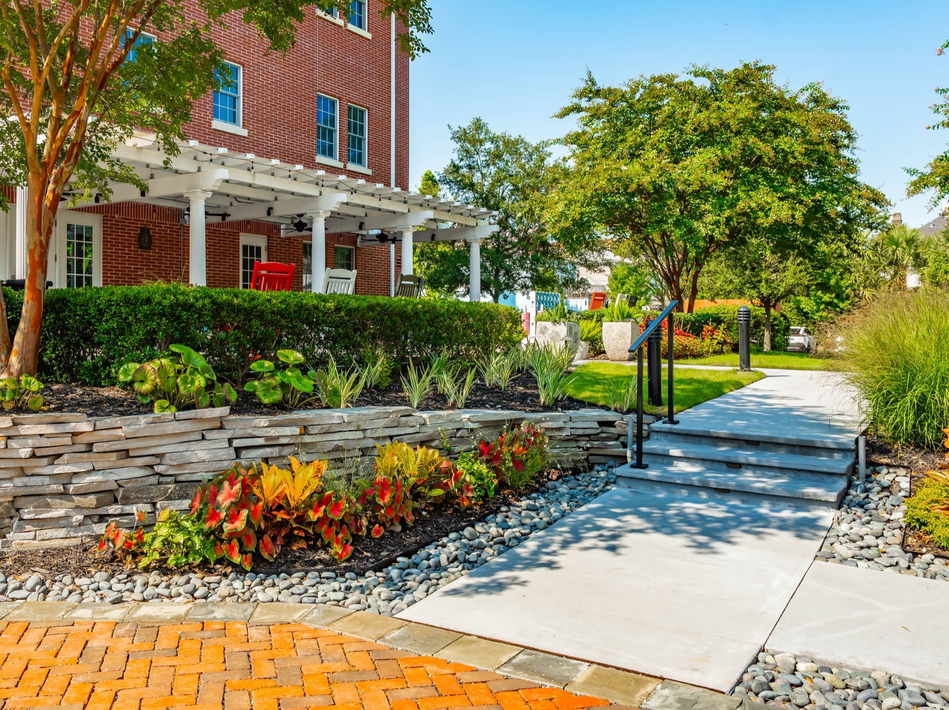 Landscaped walkway entrance with stacked stone planting beds, steps, and the pergola-covered patio behind.