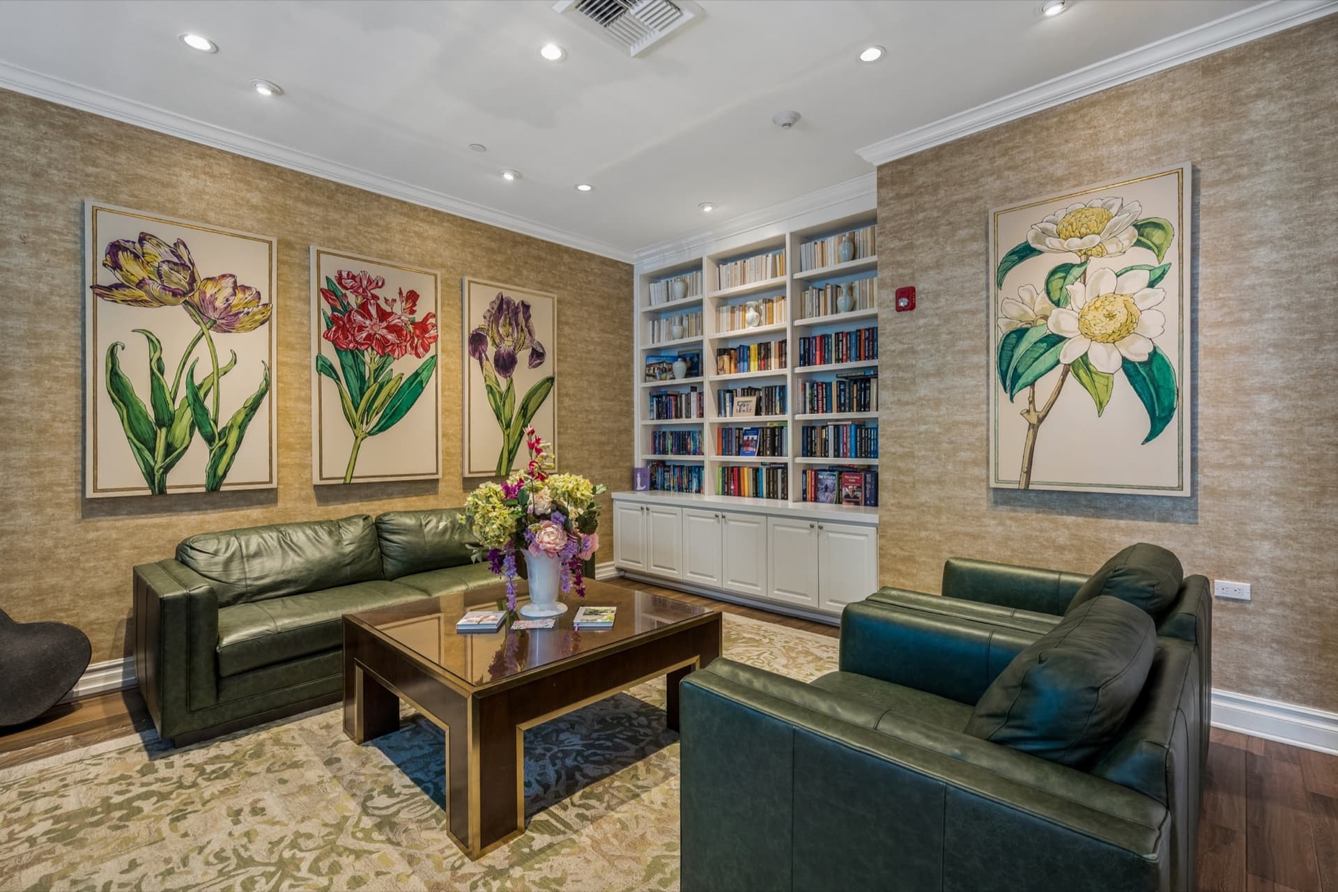 Library with green leather sofas, built-in bookshelves, and large framed botanical artwork.