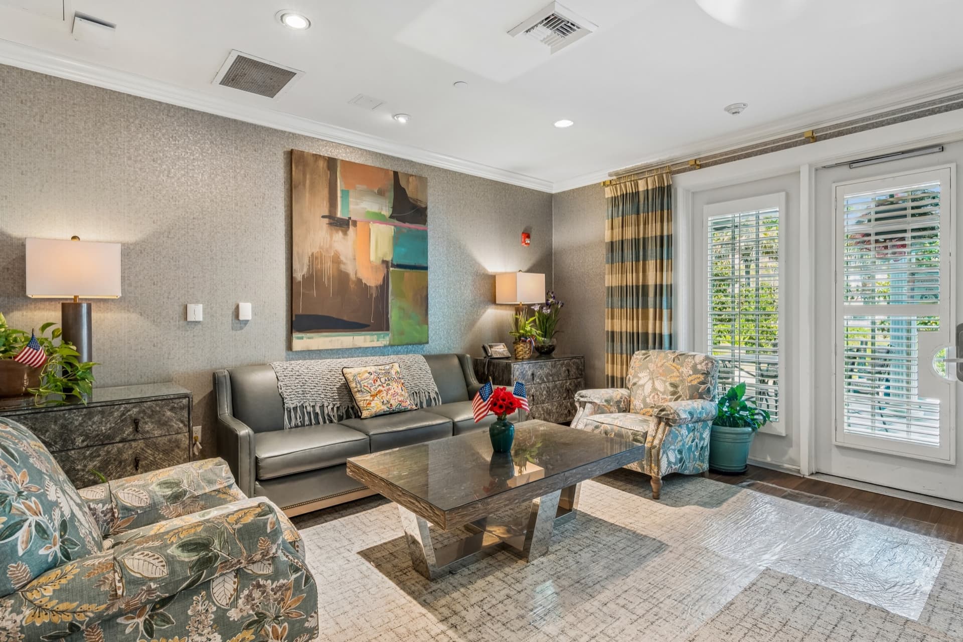 Sitting area with a leather sofa, armchairs, and French doors opening toward the garden.