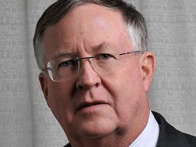 Portrait of Dr. James K. Elsey, Treasurer of Friends of Fisher House Charleston, wearing wire-rimmed glasses and a dark suit