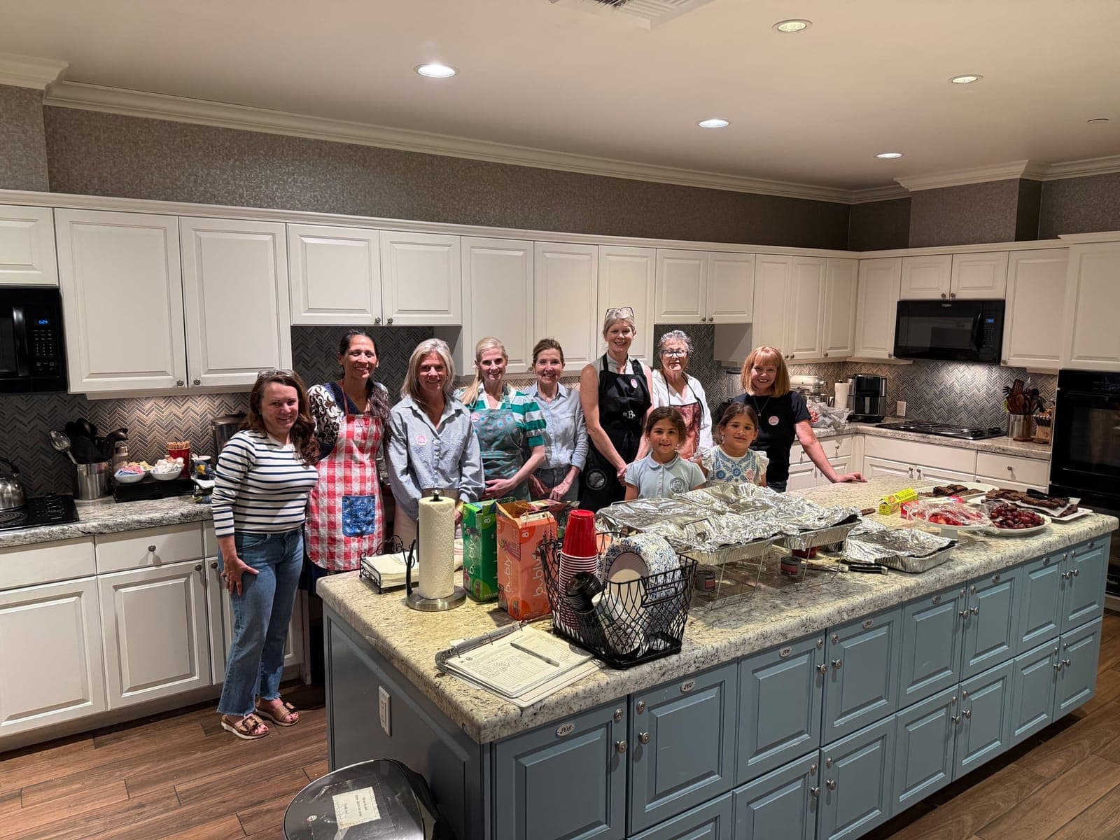 Harleston Village Association volunteers gathered in the Fisher House kitchen with trays of home-cooked food
