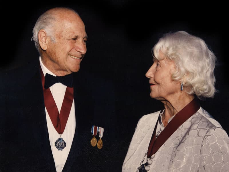 Zachary and Elizabeth Fisher in evening dress, facing each other, both wearing decorations on ribbons